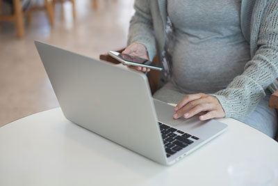 pregnant woman using phone and computer to contact us
